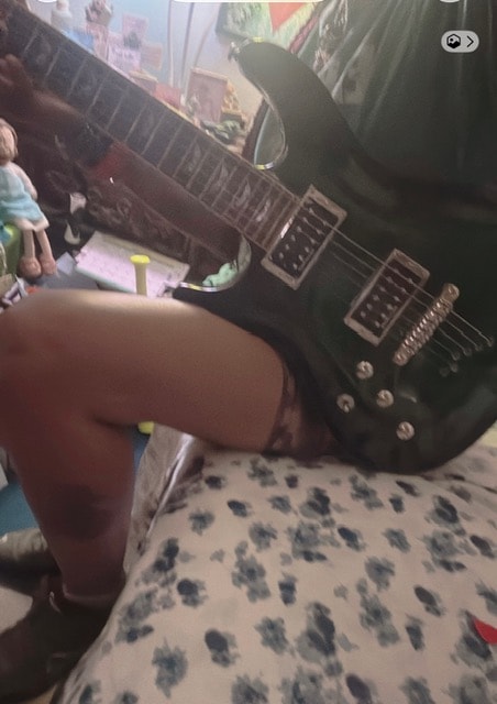 Andrea playing green electric guitar